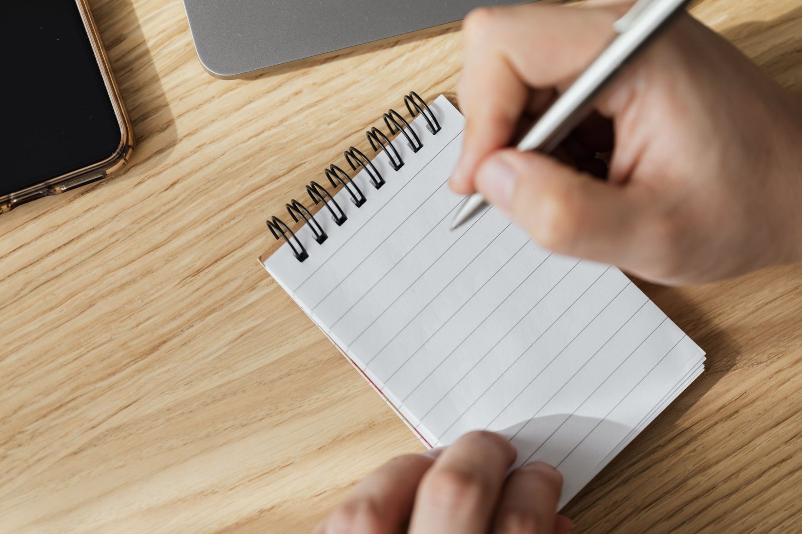 Mano con bolígrafo sobre un cuaderno en blanco para escribir qué te falta